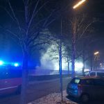 Eine Rauchwolke steigt aus einer Tiefgarageneinfahrt auf. Davor ein Feuerwehrfahrzeug mit aktivem Blaulicht.